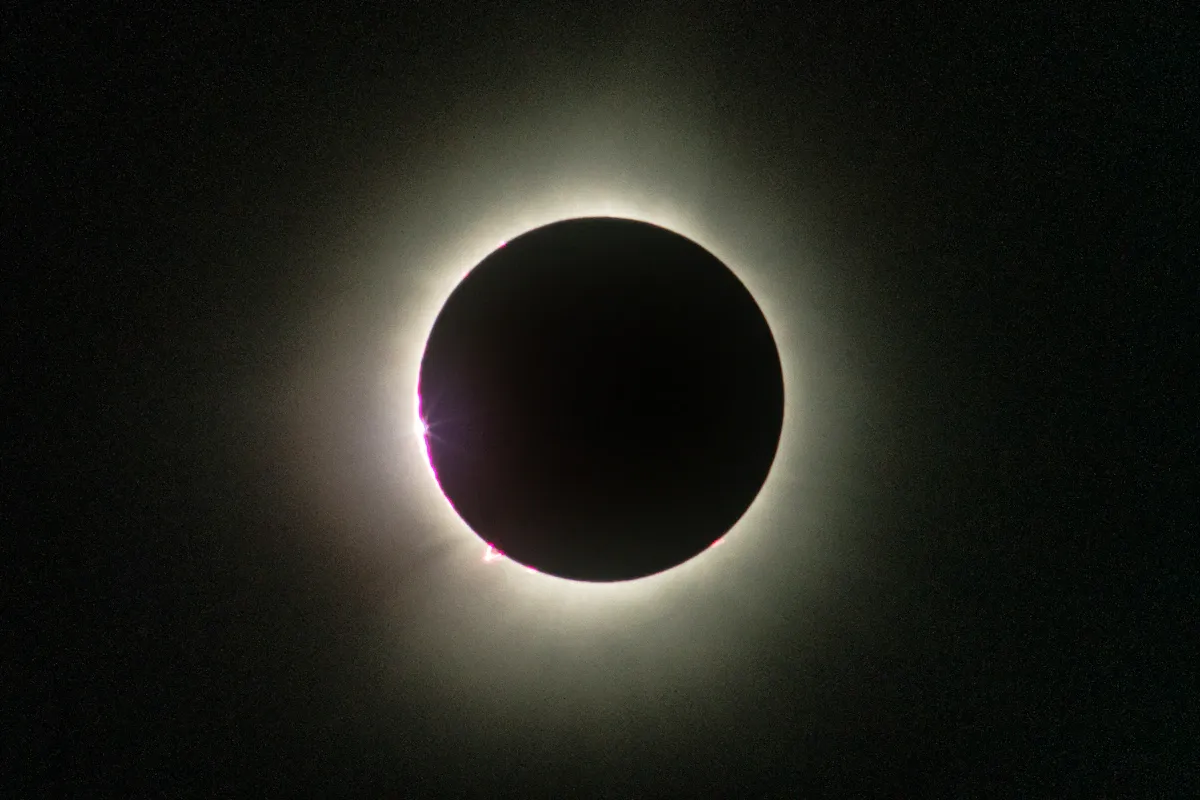 Total solar eclipse viewed from deep space with the Moon's cratered surface close up against a dark sky