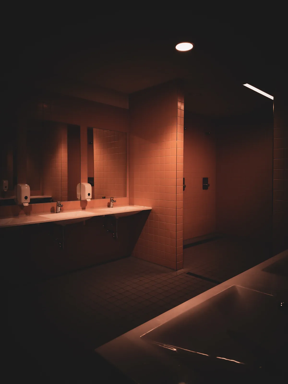 Dimly lit bathroom at night with soft candlelight glow, creating a calming dark showering atmosphere
