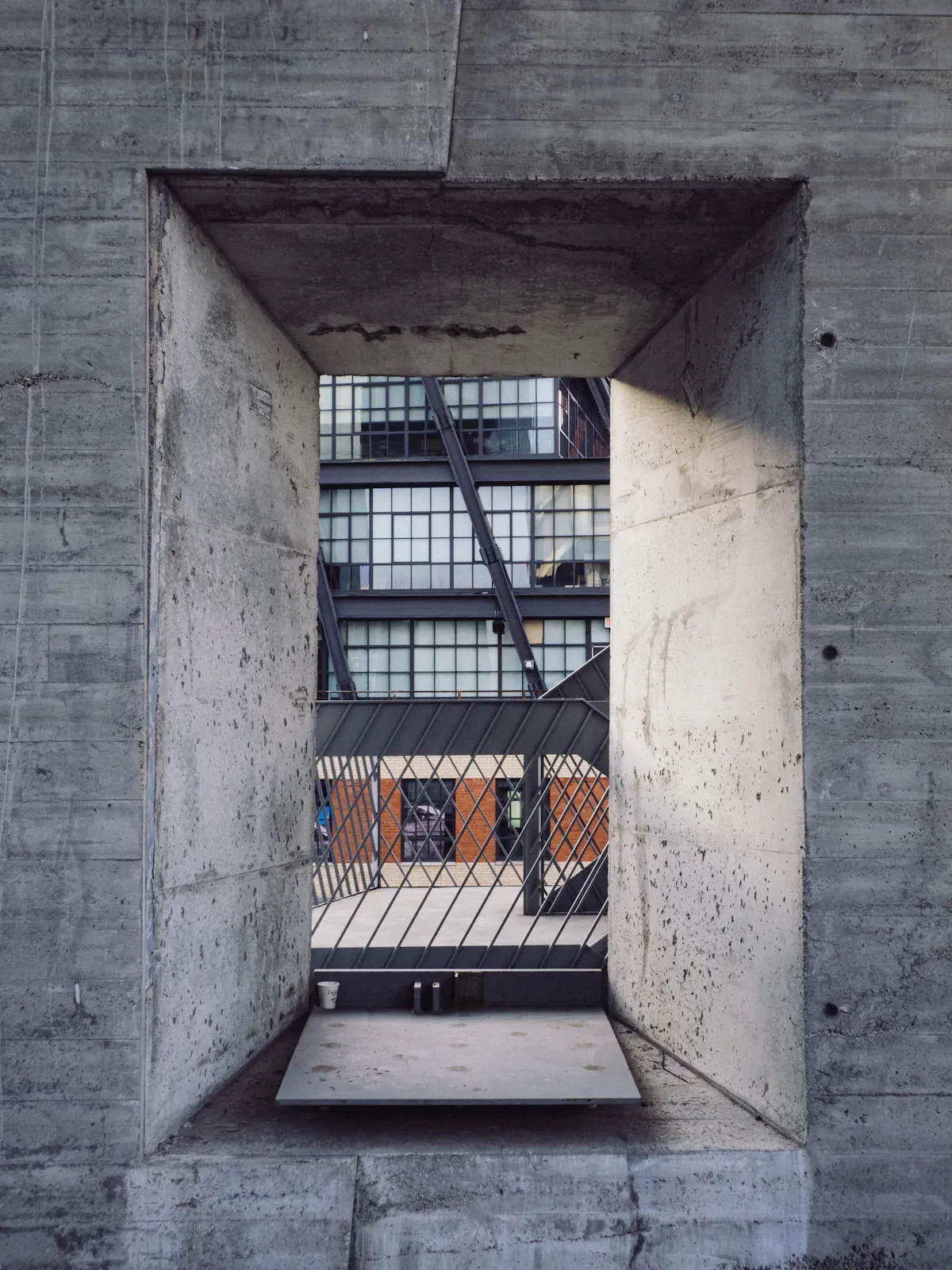 Beton binalar ve asfalt yollarla kaplı doğasız bir şehir manzarası, yeşil alanın eksikliği vurgulanıyor.