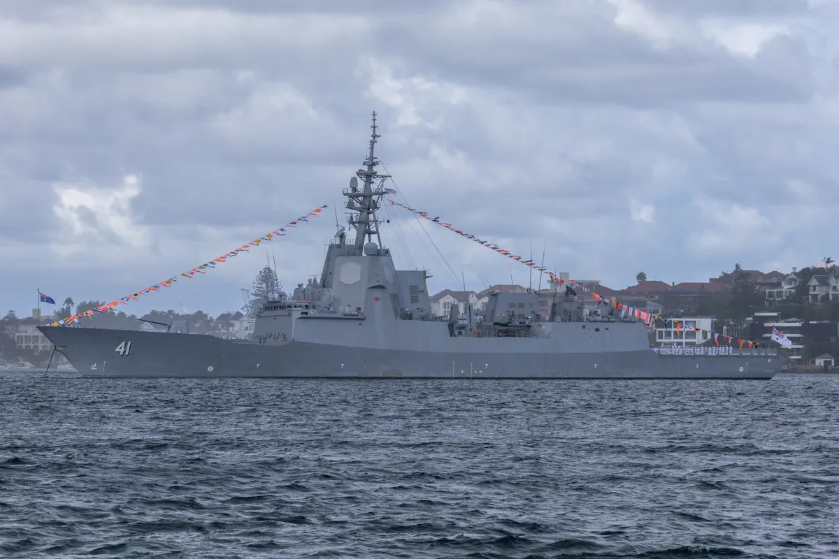 Mavi sularda ilerleyen büyük bir deniz güvenliği gemisi, geniş okyanus manzarasıyla karanlık gökyüzü altında