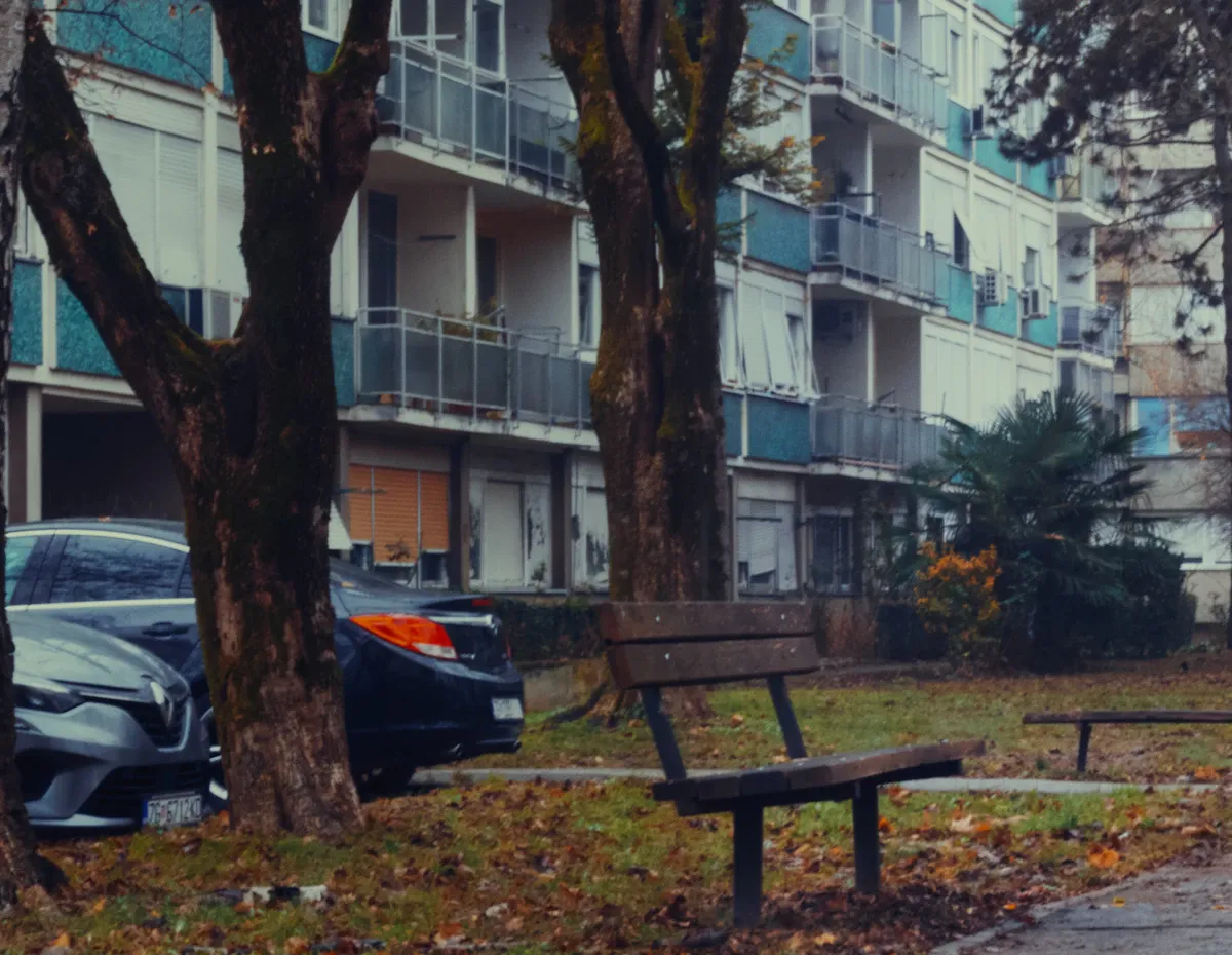 Boş bir mahalle parkında tek başına duran ve üçüncü mekânların yok oluşunu simgeleyen tahta park bankı.