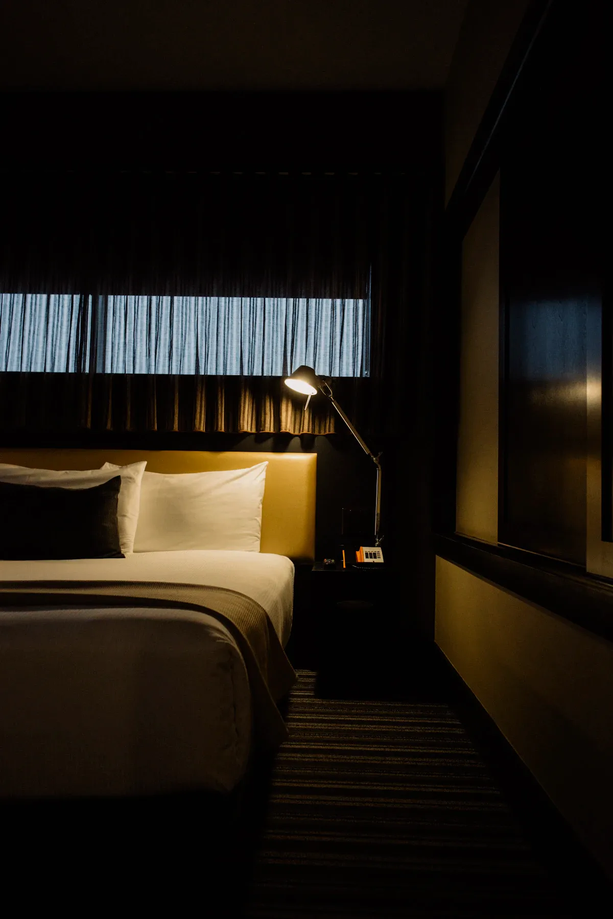 Karanlık bir yatak odasında geceleyin parlayan telefon ekranı, uyku erteleme sorununu temsil ediyor.